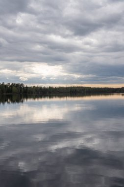 Baharda güzel bir göl, dinamik gri gökyüzü, bulutlar. Sudaki yansıma. Dinlenmek için yer.