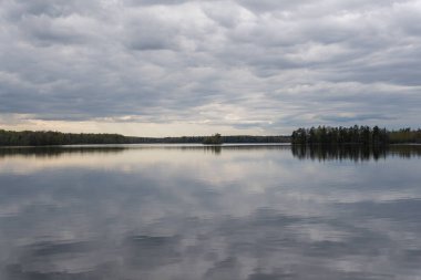 Baharda güzel bir göl, dinamik gri gökyüzü, bulutlar. Sudaki yansıma. Dinlenmek için yer.