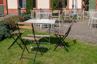 Sandalyeler ve açık havada dinlenmek için masa. Rahatlatıcı bölge. Sıcak ve rahat bir atmosfer. Güneşli bir gün. Kafe. 