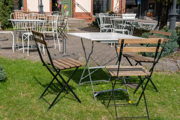 Sandalyeler ve açık havada dinlenmek için masa. Rahatlatıcı bölge. Sıcak ve rahat bir atmosfer. Güneşli bir gün. Kafe. 