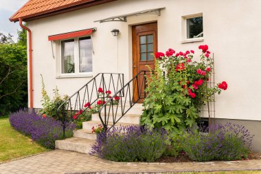 Beautiful yard, entry of a private house in Europe. Stylish architecture, concept of a building. Decorated facade. A lot of greenery and flowers on a summer day. Urbanism.