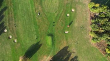 Sonbaharda yeşil bir golf sahasında hava manzarası. Golf müsabakaları, golfçüler. Ağaçların büyük ve güzel gölgeleri.  