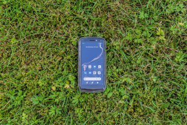 Sweden, Knislinge  July 24, 2022: A compact little portable Android smartphone on a green grass