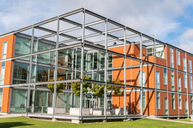 Modern mimari, ofis merkezi kavramı. İş merkezinin yakınında küçük ağaçlar olan yeşil alan. Etkileyici ve alışılmadık bir tasarım. Şehirdeki ekoloji. Şehircilik. Yeşil eğlence alanı.