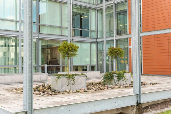 Modern mimari, ofis merkezi kavramı. İş merkezinin yakınında küçük ağaçlar olan yeşil alan. Etkileyici ve alışılmadık bir tasarım. Şehirdeki ekoloji. Şehircilik. Yeşil eğlence alanı.