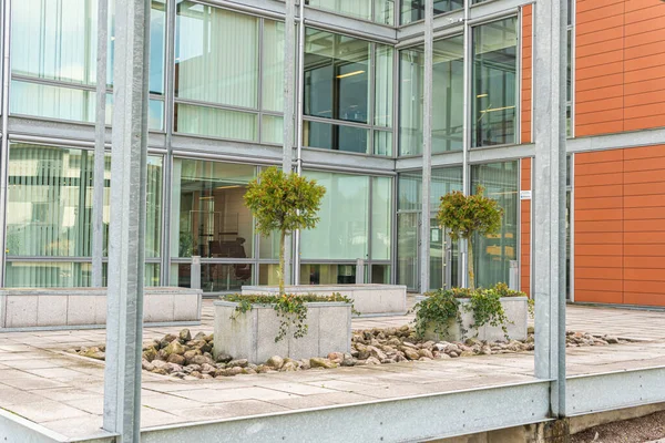 Modern mimari, ofis merkezi kavramı. İş merkezinin yakınında küçük ağaçlar olan yeşil alan. Etkileyici ve alışılmadık bir tasarım. Şehirdeki ekoloji. Şehircilik. Yeşil eğlence alanı.