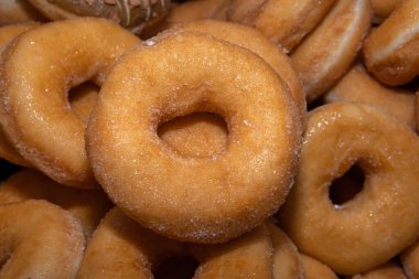 Tatlı ve lezzetli yuvarlak çörekler, şekerle kaplı halka çörekler. Çikolatalı donutlu donut. Şekerin sembolü, kızarmış hamur. Bir sürü tatlı, sağlıksız yemek. Gıda atıkları, gıda üretimi.