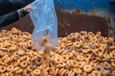 Tatlı ve lezzetli yuvarlak çörekler, şekerle kaplı halka çörekler. Çikolatalı donutlu donut. Şekerin sembolü, kızarmış hamur. Bir sürü tatlı, sağlıksız yemek. Gıda atıkları, gıda üretimi.