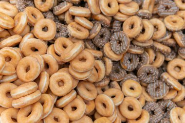 Tatlı ve lezzetli yuvarlak çörekler, şekerle kaplı halka çörekler. Çikolatalı donutlu donut. Şekerin sembolü, kızarmış hamur. Bir sürü tatlı, sağlıksız yemek. Gıda atıkları, gıda üretimi.