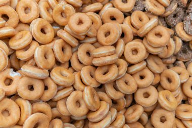 Tatlı ve lezzetli yuvarlak çörekler, şekerle kaplı halka çörekler. Çikolatalı donutlu donut. Şekerin sembolü, kızarmış hamur. Bir sürü tatlı, sağlıksız yemek. Gıda atıkları, gıda üretimi.