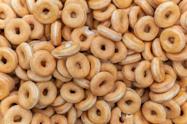 Tatlı ve lezzetli yuvarlak çörekler, şekerle kaplı halka çörekler. Çikolatalı donutlu donut. Şekerin sembolü, kızarmış hamur. Bir sürü tatlı, sağlıksız yemek. Gıda atıkları, gıda üretimi.