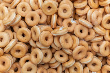 Tatlı ve lezzetli yuvarlak çörekler, şekerle kaplı halka çörekler. Çikolatalı donutlu donut. Şekerin sembolü, kızarmış hamur. Bir sürü tatlı, sağlıksız yemek. Gıda atıkları, gıda üretimi.
