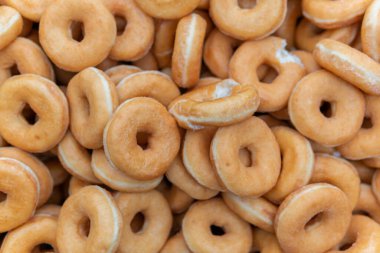Tatlı ve lezzetli yuvarlak çörekler, şekerle kaplı halka çörekler. Çikolatalı donutlu donut. Şekerin sembolü, kızarmış hamur. Bir sürü tatlı, sağlıksız yemek. Gıda atıkları, gıda üretimi.