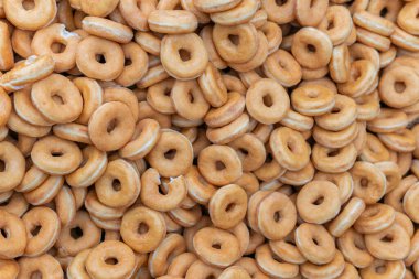 Tatlı ve lezzetli yuvarlak çörekler, şekerle kaplı halka çörekler. Çikolatalı donutlu donut. Şekerin sembolü, kızarmış hamur. Bir sürü tatlı, sağlıksız yemek. Gıda atıkları, gıda üretimi.