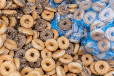 Tatlı ve lezzetli yuvarlak çörekler, şekerle kaplı halka çörekler. Çikolatalı donutlu donut. Şekerin sembolü, kızarmış hamur. Bir sürü tatlı, sağlıksız yemek. Gıda atıkları, gıda üretimi.