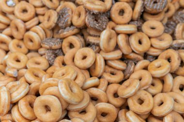 Tatlı ve lezzetli yuvarlak çörekler, şekerle kaplı halka çörekler. Çikolatalı donutlu donut. Şekerin sembolü, kızarmış hamur. Bir sürü tatlı, sağlıksız yemek. Gıda atıkları, gıda üretimi.