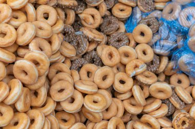 Tatlı ve lezzetli yuvarlak çörekler, şekerle kaplı halka çörekler. Çikolatalı donutlu donut. Şekerin sembolü, kızarmış hamur. Bir sürü tatlı, sağlıksız yemek. Gıda atıkları, gıda üretimi.