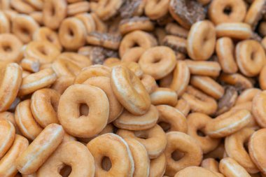 Tatlı ve lezzetli yuvarlak çörekler, şekerle kaplı halka çörekler. Çikolatalı donutlu donut. Şekerin sembolü, kızarmış hamur. Bir sürü tatlı, sağlıksız yemek. Gıda atıkları, gıda üretimi.