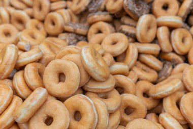 Tatlı ve lezzetli yuvarlak çörekler, şekerle kaplı halka çörekler. Çikolatalı donutlu donut. Şekerin sembolü, kızarmış hamur. Bir sürü tatlı, sağlıksız yemek. Gıda atıkları, gıda üretimi.