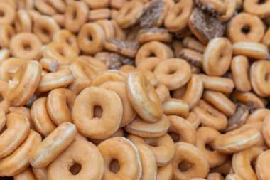 Tatlı ve lezzetli yuvarlak çörekler, şekerle kaplı halka çörekler. Çikolatalı donutlu donut. Şekerin sembolü, kızarmış hamur. Bir sürü tatlı, sağlıksız yemek. Gıda atıkları, gıda üretimi.