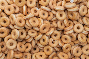 Tatlı ve lezzetli yuvarlak çörekler, şekerle kaplı halka çörekler. Çikolatalı donutlu donut. Şekerin sembolü, kızarmış hamur. Bir sürü tatlı, sağlıksız yemek. Gıda atıkları, gıda üretimi.