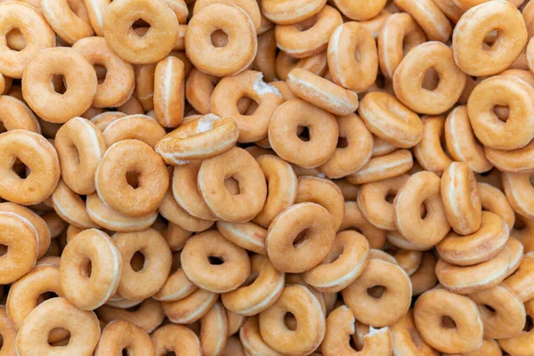 stock image Many sweet and tasty round doughnuts, ring donuts covered with sugar. Chocolate-frosted doughnut. Symbol of sweeties, fried dough. A lot of sweet unhealthy food. Food waste, food production.