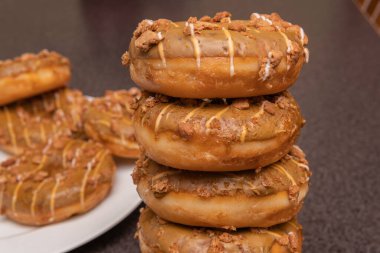 Tatlı ve lezzetli yuvarlak çörekler, şekerle kaplı halka çörekler. Çikolatalı donutlu donut. Şekerin sembolü, kızarmış hamur. Bir sürü tatlı, sağlıksız yemek. Gıda atıkları, gıda üretimi.