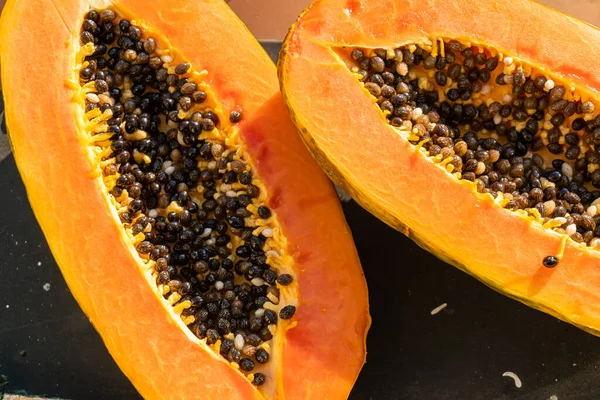 Sıcak ve güneşli bir günde pencere kenarında iki papaya. Papaya ikiye bölündü..