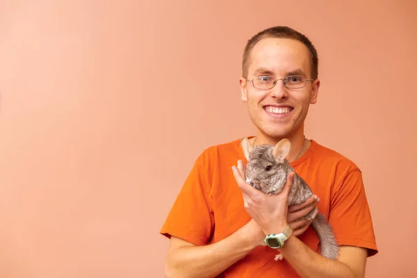 A man is posing with chinchilla. Animal-Assisted, Pet Therapy. Playful and tamed chinchilla.