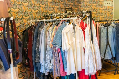 İsveç, Malmö 8 Temmuz 2023: Askılarda farklı giysiler, ikinci el mağazasında asılı kıyafetler