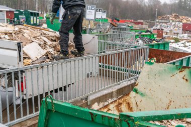 İsveç, Malmö 13 Mart 2023: Çöp toplama istasyonundaki enkazı sıralayan bir adam. Çöp ve atık dolu bir sürü büyük konteynır..