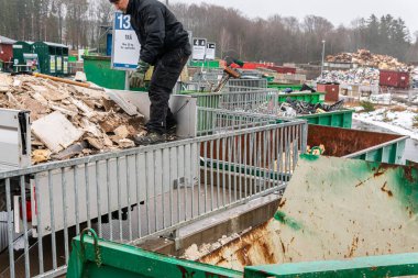 İsveç, Malmö 13 Mart 2023: Çöp toplama istasyonundaki enkazı sıralayan bir adam. Çöp ve atık dolu bir sürü büyük konteynır..