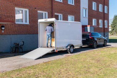 İsveç, Malmö 2 Nisan 2023: Erkekler eşyaları büyük bir karavana yüklüyor. Farklı eşyalarla dolu bir minibüsü paketlemek, taşınmak....