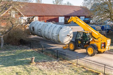 İsveç, Malmö 3 Nisan 2023: Telgraf idarecisi ve ön-uçtaki yükleyiciyle büyük bir sanayi bölgesinin taşınması 