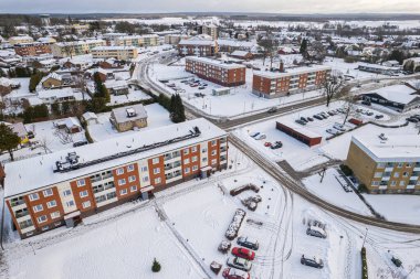 İsveç 'te kışın alçak katlı ve özel binaları olan yerleşim alanının havadan görüntüsü. Karlı hava, küçük bir Avrupa köyünde kar yağışı, kasaba, şehir.