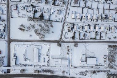 İsveç 'te kışın alçak katlı ve özel binaları olan yerleşim alanının havadan görüntüsü. Karlı hava, küçük bir Avrupa köyünde kar yağışı, kasaba, şehir.