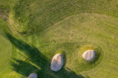 Golf course in summer during sunset, drone shot. Beautiful shadows and green manicured field. clipart