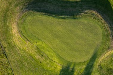 Yazın gün batımında golf sahası, İHA atışı. Güzel gölgeler ve yeşil manikürlü tarla.