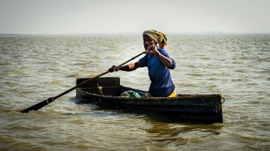 Ishwardi, Bangladeş - 10.2022: derme çatma teknedeki zavallı Bengalli Ganj nehrinde yüzüyor. Nehrin ortasındaki bir teknede balıkçı..