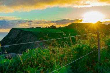 Sunrise sun over green hills by Atlantic Ocean. Basque country, Spain. Way of St. James, El Camino de Santiago