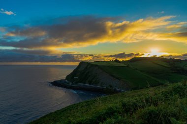 Sunrise over green hills and cliffs on the ocean coast near Orio, Basque Country, Spain. The Way of St. James, El Camino de Santiago.