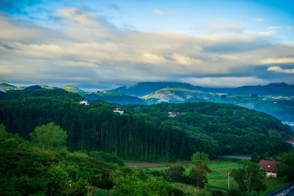 landscape with forest and mountains, in the background mountain peaks in the clouds. Basque Country, Spain