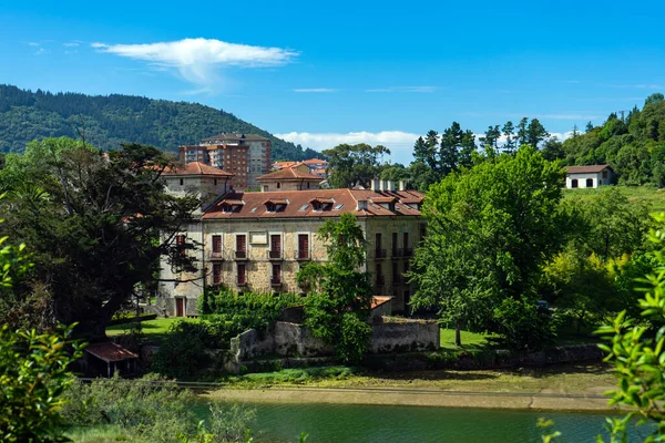 old manor house on the river bank against the background of high-rise buildings. Spain, Basque Country