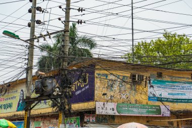 Bangladeş, Rajshahi - 04.21.2023: Şehrin caddesindeki elektrik kablolarından sayısız elektrik kablosu sarkıyor