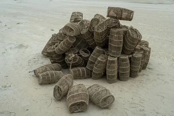 stock image pile of empty, cylindrical wire crab traps on sandy surface, near coastal area,fishing equipment used for crabbing, shrimp