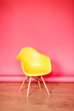 Pembe arka planda sarı, modern bir sandalye. En düşük iç tasarım.