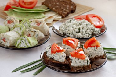 Süzme peynirli sebzeli sandviç, domates ve yeşillikler beyaz arka planda. Atıştırmalık çeşitleri