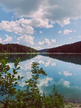 Mavi gökyüzü ile güzel dağ gölü ve suya yansıyan bulutlar. Kara Göl 'deki bulutların yansıması, Zhabljak, Karadağ. 