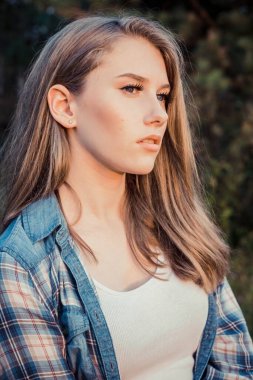 Doğal uzun saçlı genç sarışın manken düşünceli bir şekilde uzaklarda görünüyor. 