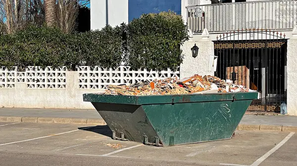 Konut binasının yakınındaki moloz ve enkaz dolu yeşil konteynır. 